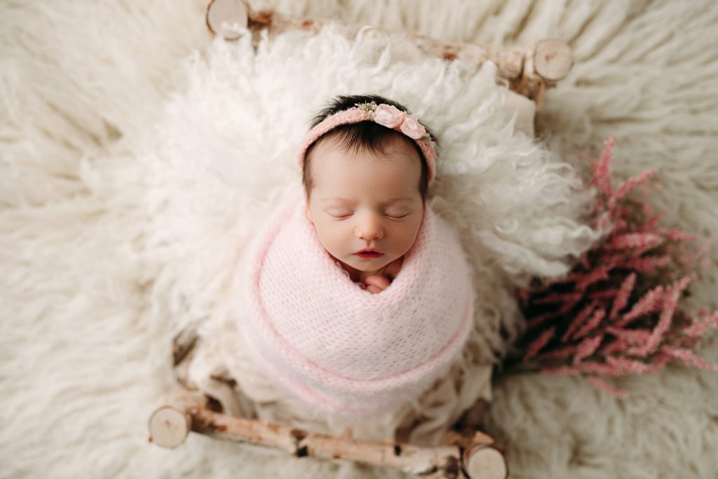 newborn in pink wrap photo session