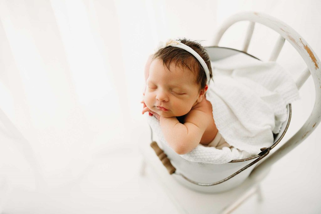 newborn girl in bucket on a chair