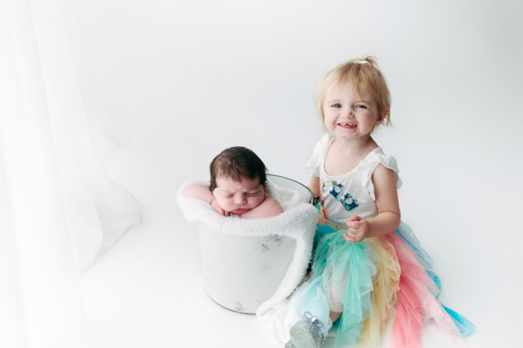 sister with newborn brother in a bucket