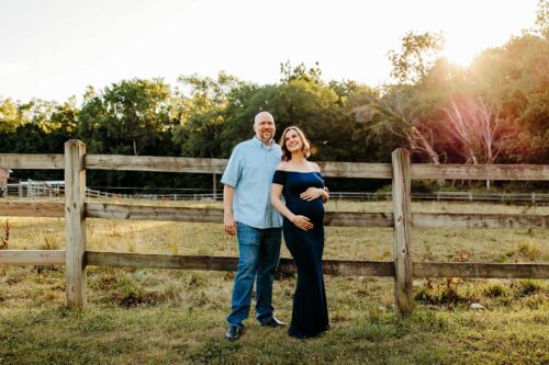 pregnant couple outside by horse fence