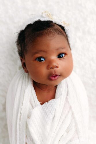 dark skinned baby girl swaddled on lace
