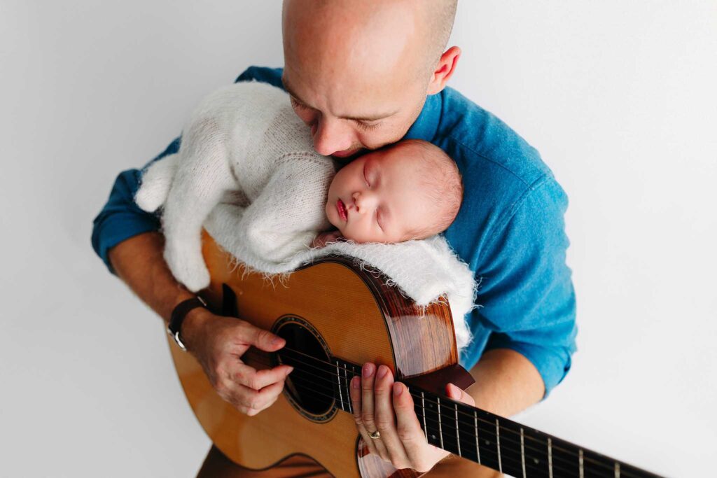 newborn sleeping on dads guitar