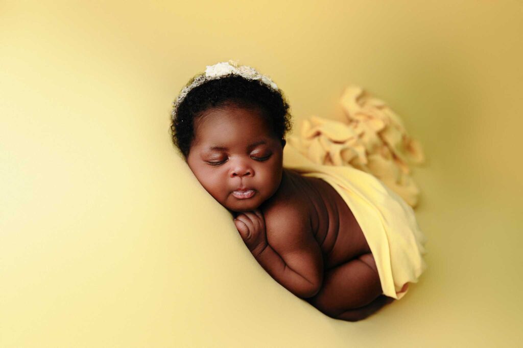 african baby sleeping on yellow backdrop