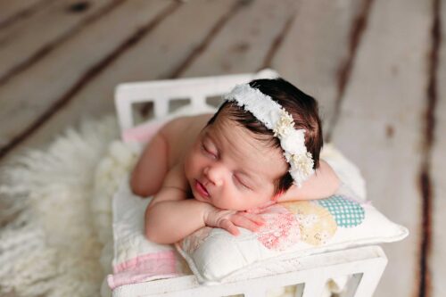 newborn sleeping head on hands quilt pillow in bed