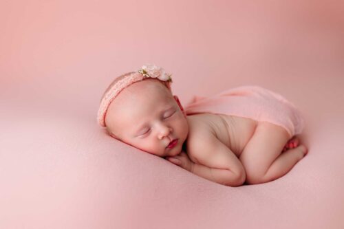 newborn in bum up with diaper covered sleeping on pink
