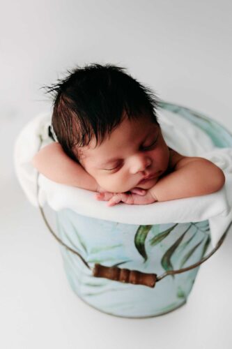newborn sleeping in white vine bucket