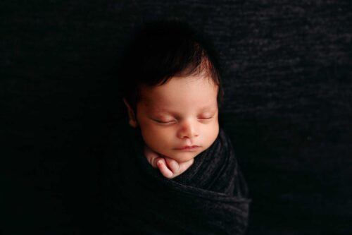 newborn in black swaddle