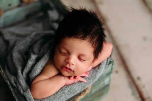 baby boy in green crate basket