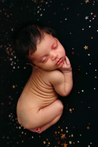 newborn boy sleeping naked on black and gold blanket