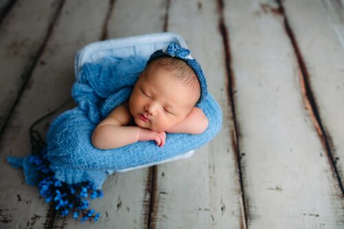 baby girl sleeping in blue sewing basket
