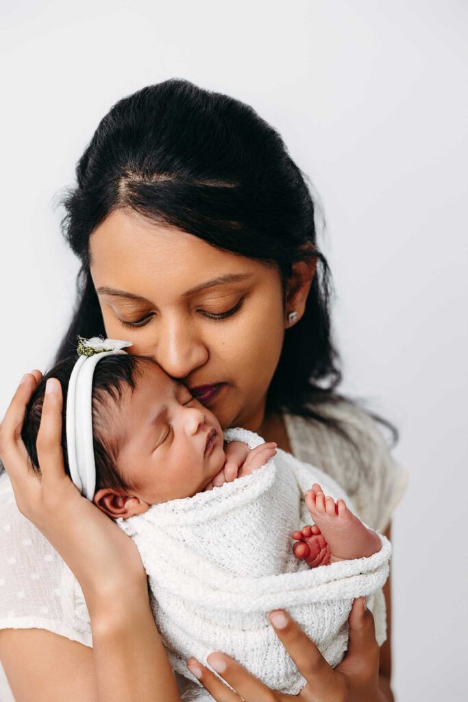 mom kissing newborn