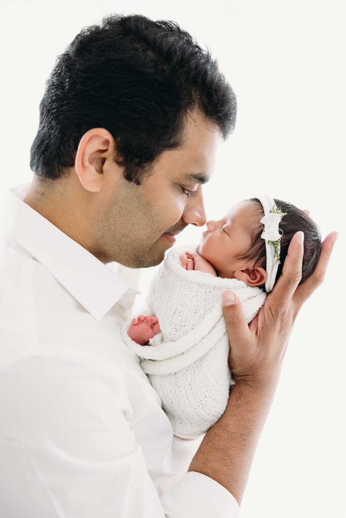 dad holding newborn by window