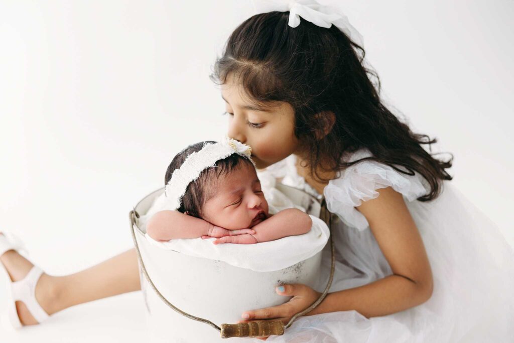 sister kissing newborn