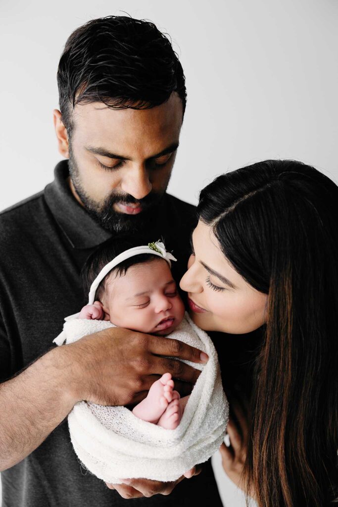 dad mom newborn wrapped in studio